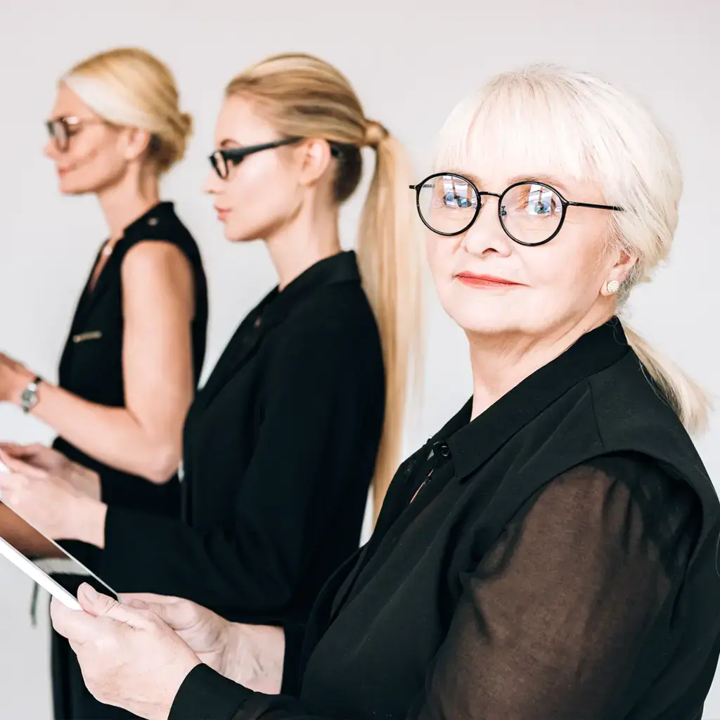 A senior businesswoman looking at the camera with colleagues.