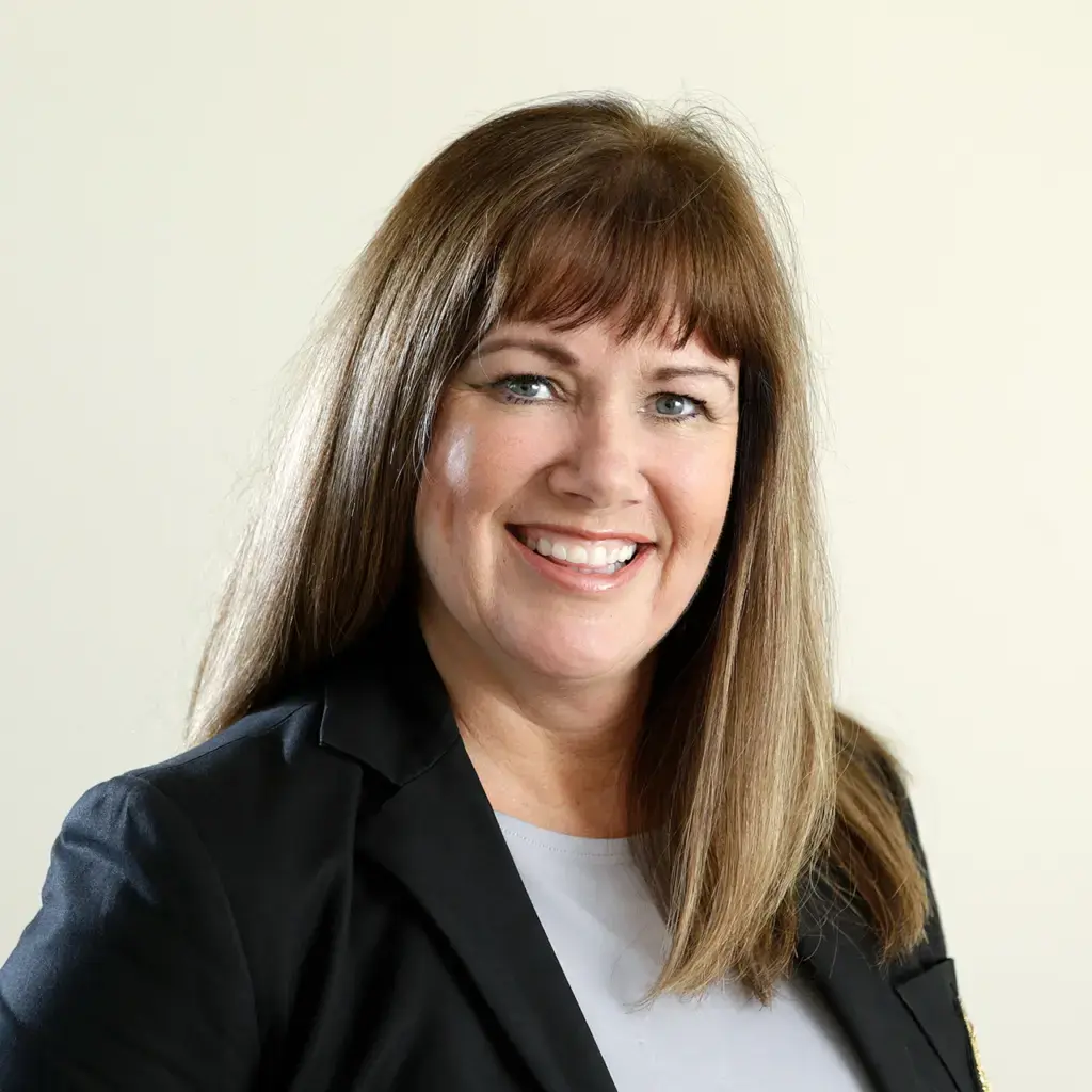 Professional headshot of a smiling woman with brown hair.