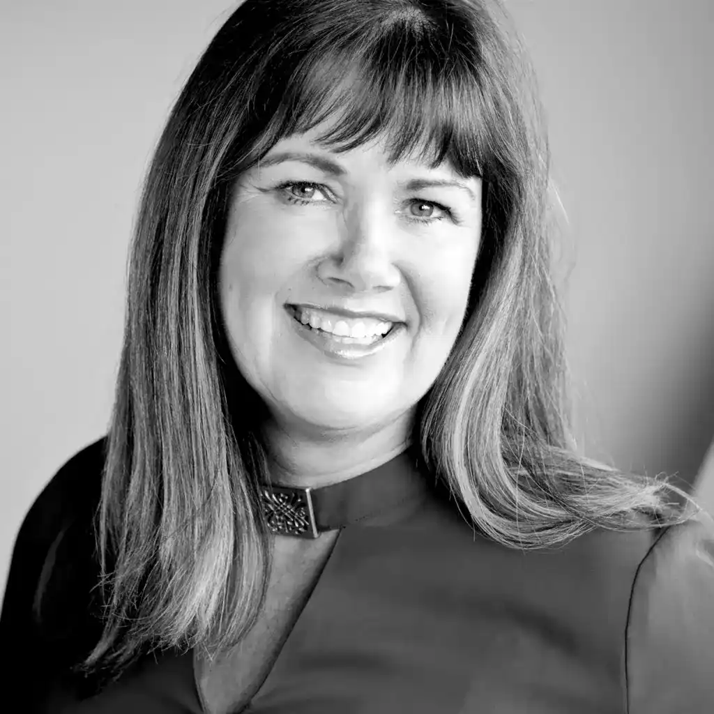 A professional black and white headshot of a smiling woman.