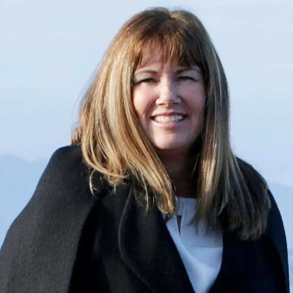 A headshot of a smiling woman with brown hair.
