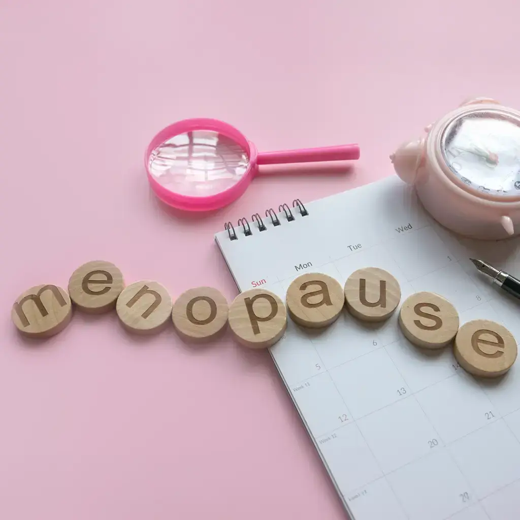 Menopause spelled in wooden letters on a pink background.
