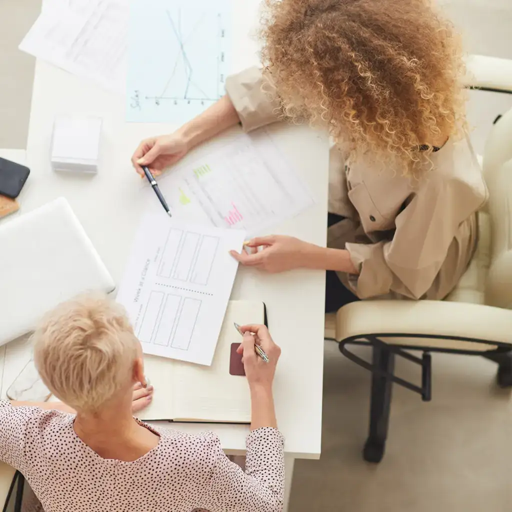 Overhead view of two women working together at a desk.