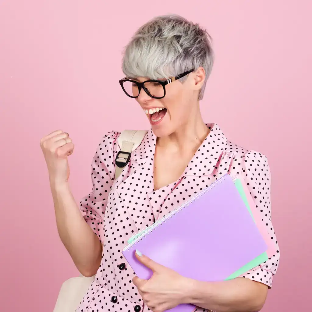 Excited student with notebooks celebrates against a pink background.