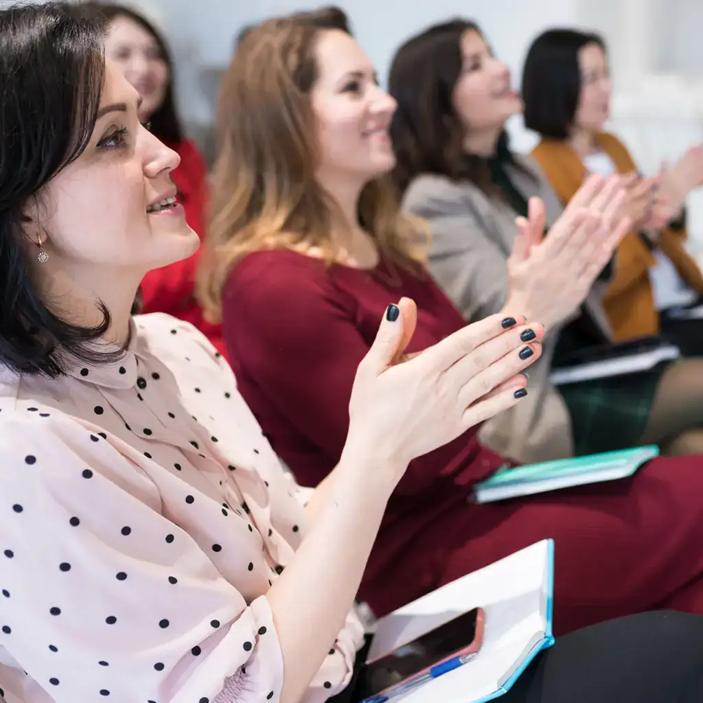A group of women clapping at a conference.
